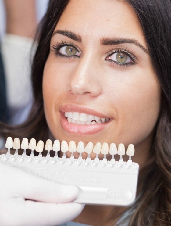 Dallas cosmetic dentist holding a row of veneers next to a smiling patient