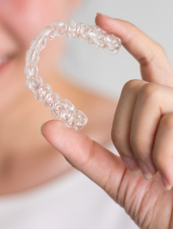 Hand holding an Invisalign clear aligner