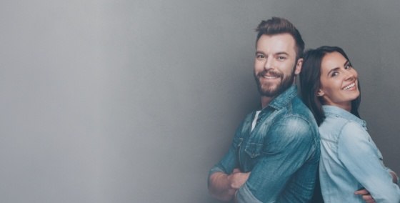 Man and woman in denim shirts smiling and standing back to back