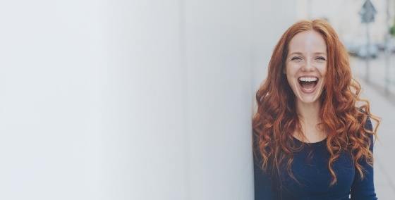 Womanw ith red hair grinning after facial and aesthetic dental services