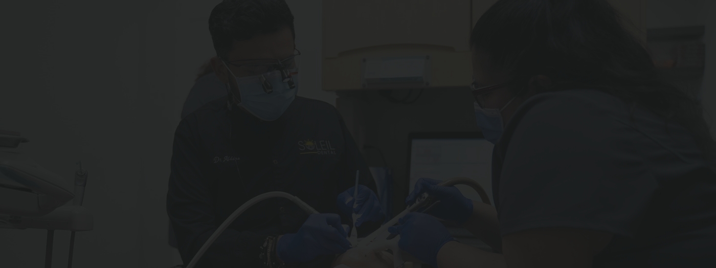 Two dentists treating a dental patient