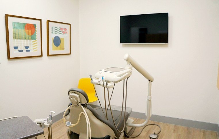 White dental treatment room with T V screen on wall