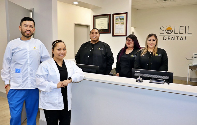 Smiling Dallas dentists and team members at front desk