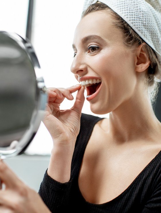 Woman placing take home teeth whitening tray over her upper teeth